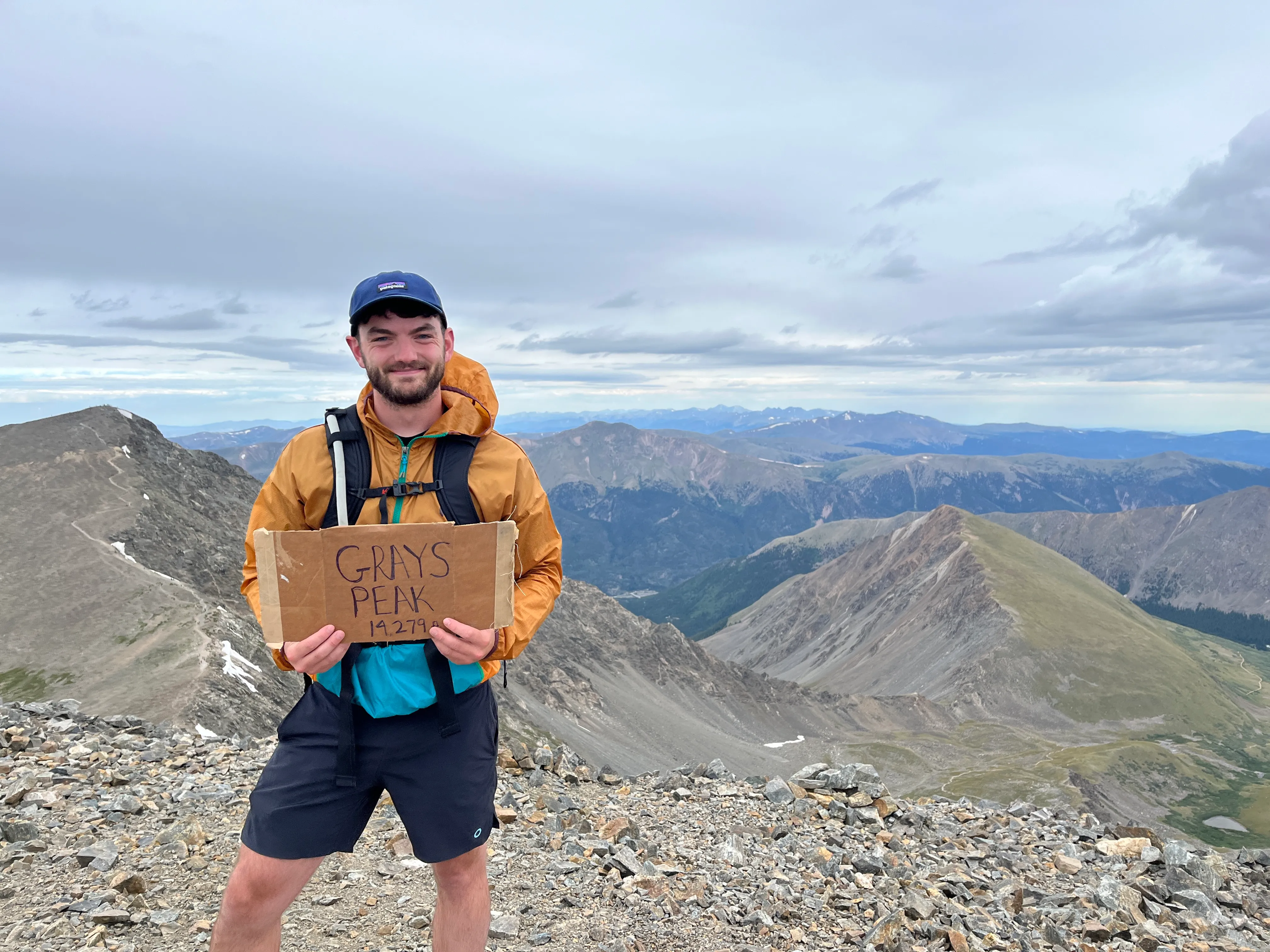 A picture of Alex Whitmore at the top of a Colorado mountain called Gray's Peak.